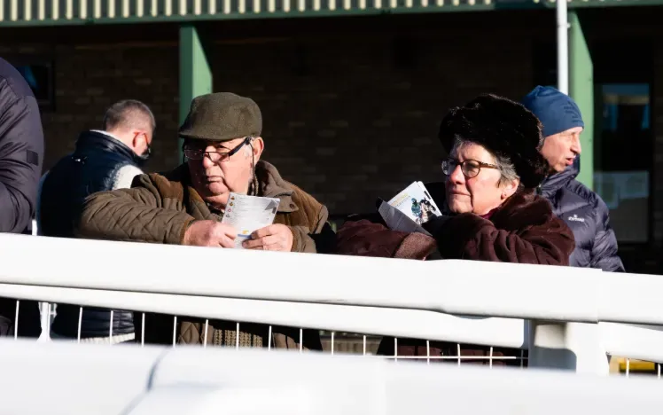 Two race goers at Hereford holding their racecards