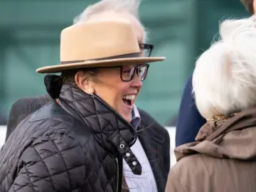 A race goer in a hat at Hereford Races laughs with friends