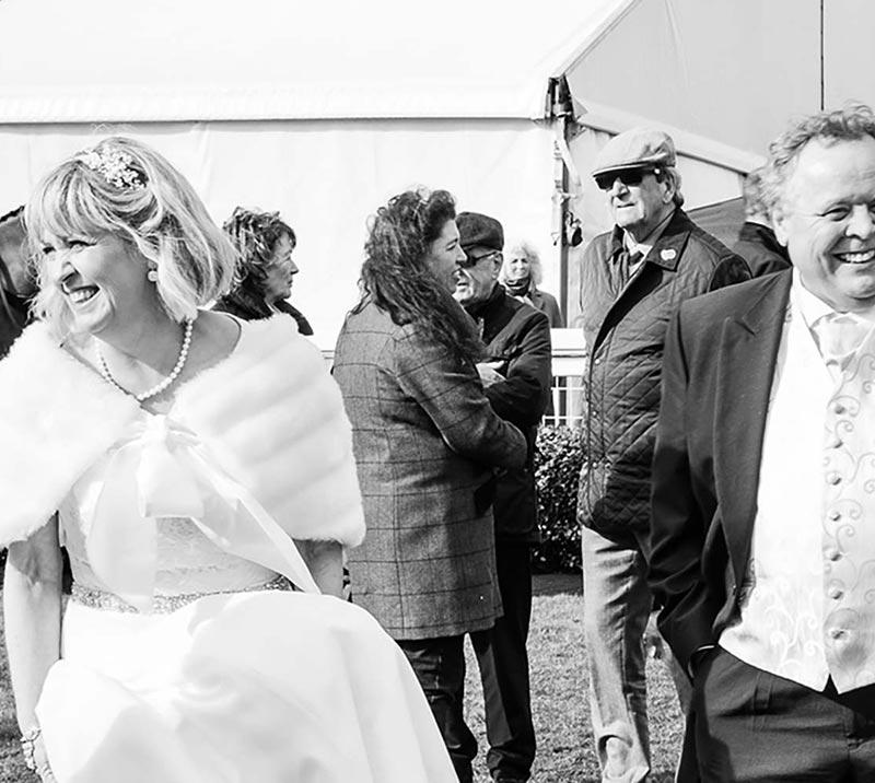 Newlyweds with their guests standing outside of the marquee.