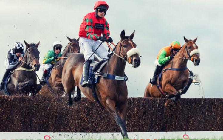 Jockeys jumping over a hurdle during a race.