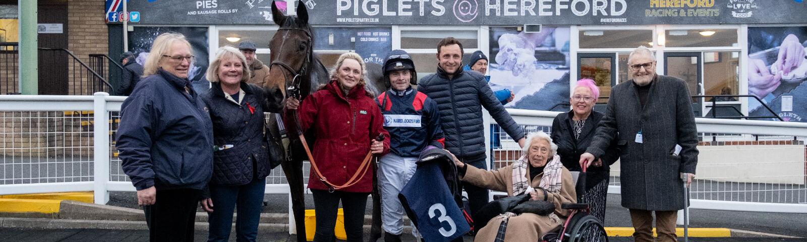 An owners and trainers group posing with their horse following a win at Hereford Racecourse