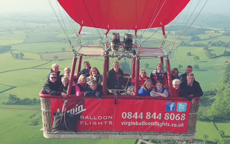 Hot air balloon with passengers inside mid-flight. 