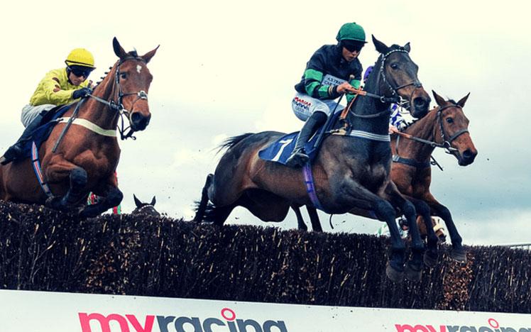 Jockeys jumping over a hurdle during a race.