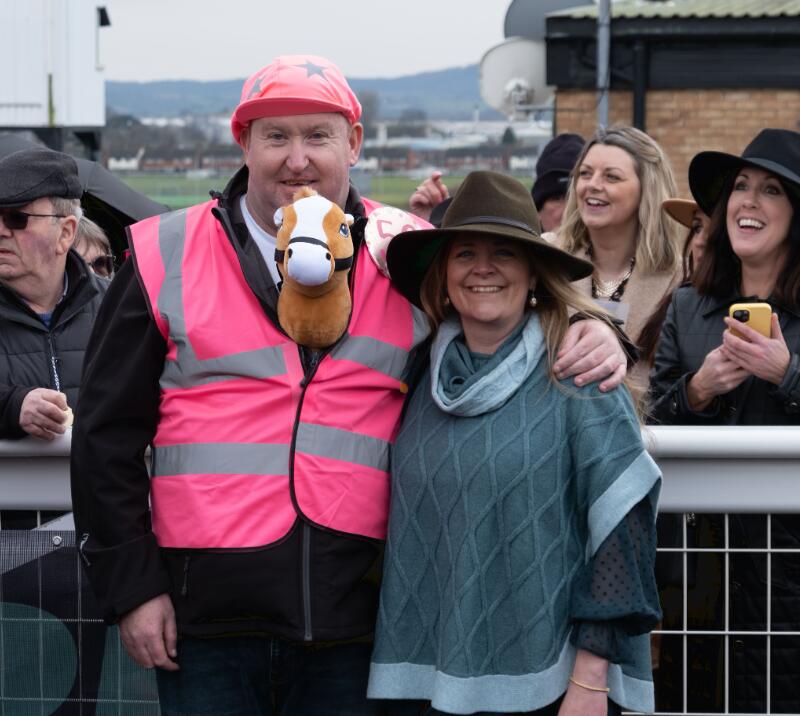 A race goer dressed as a jockey with a toy horse