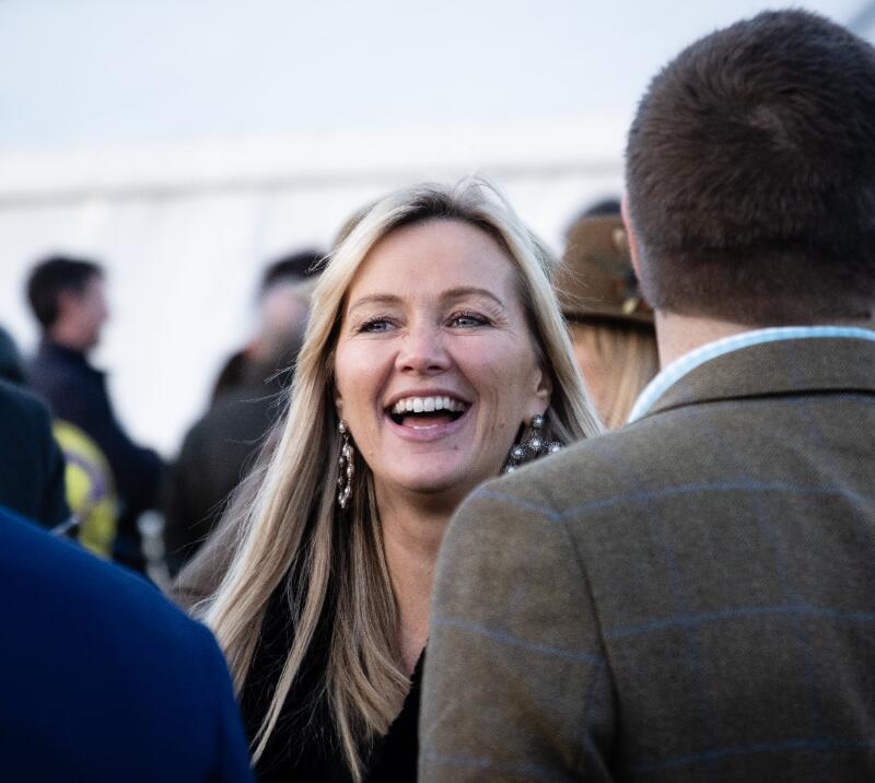 A race goer miling as she chat with friends at Hereford Racecourse.