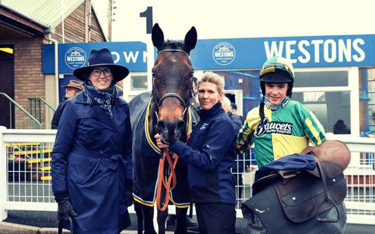 Owner, jockey posing for a photo next to their horse.