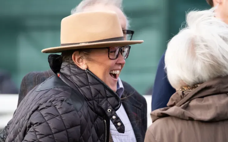 A race goer in a hat at Hereford Races laughs with friends