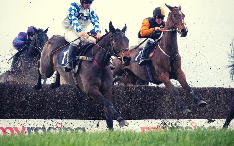 Jockeys jumping over a hurdle.