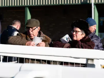 Two race goers at Hereford holding their racecards
