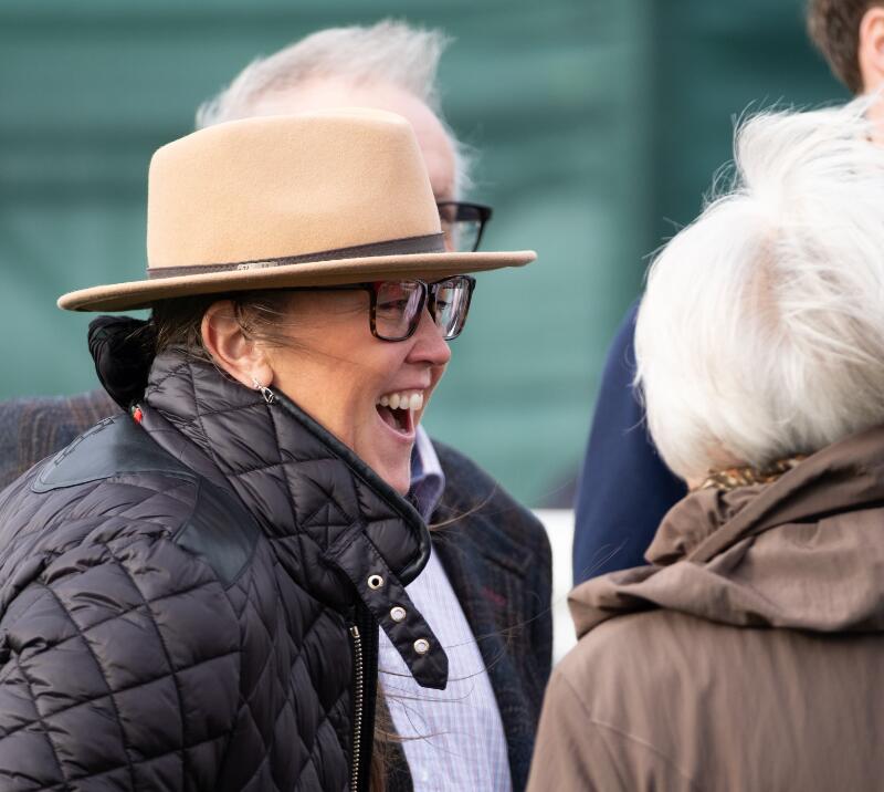 A race goer in a hat laughs with friends at Hereford Racecourse