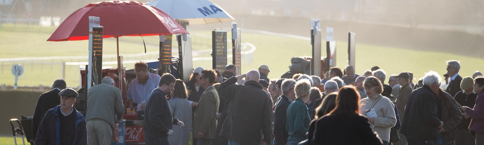 Crowds gather in front of the bookmakers at Hereford Racecourse as the sun shines down