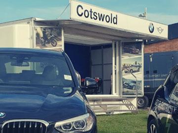Cars parked in front of an exhibition stand at an event.